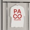 Camiseta oversize blanca de Paco de Lucía con diseño tipográfico rojo, colgada en una percha